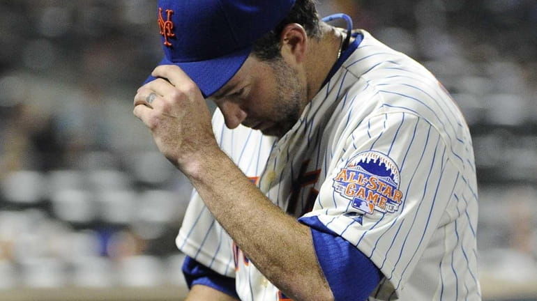 Mets starting pitcher Shaun Marcum enters the dugout after being...
