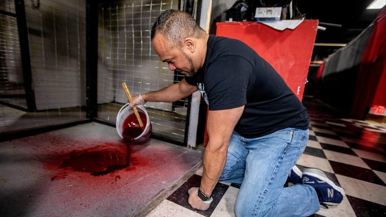 Oscar Gonzalez paints blood at the base of a hanging...