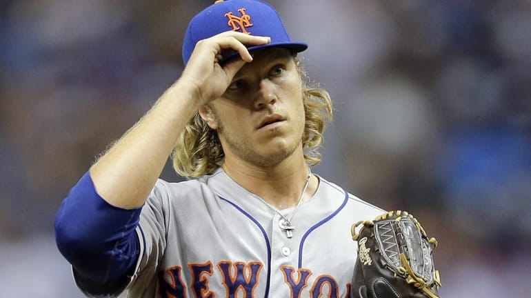 New York Mets' Noah Syndergaard adjusts his cap during the...
