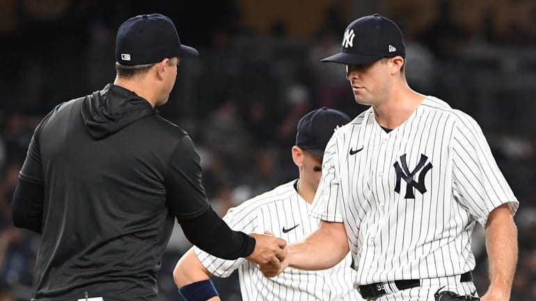 Yankees relief pitcher Clay Holmes hands the ball to manager...