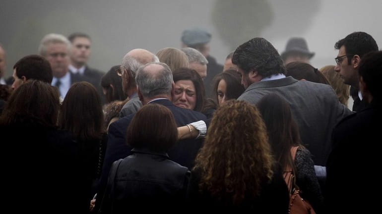 Mourners grieve following a ceremony before the casket of James...