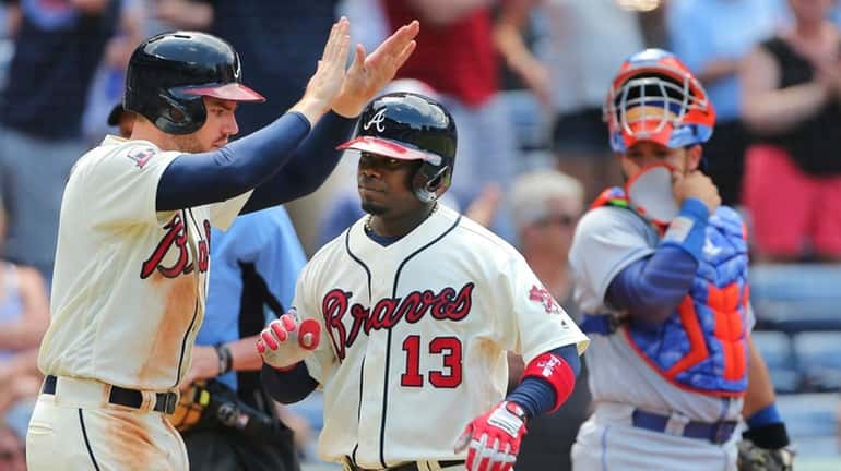 The Braves' Adonis Garcia is greeted at home plate by...