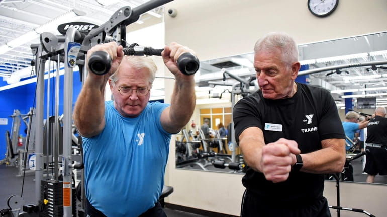Personal trainer Wayne Ruben of Northport, right, works with his...