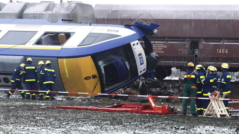 Police officers inspect an overturned passenger train after a train...
