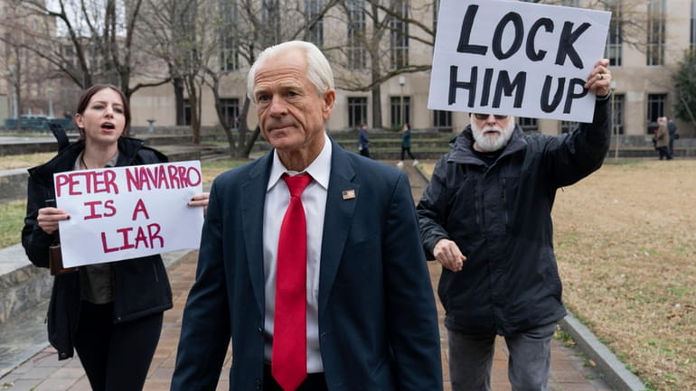 Former Trump White House official Peter Navarro, followed by demonstrators,...