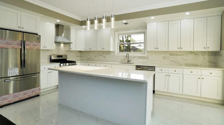 The spacious eat-in kitchen has a large island, marble countertops and...