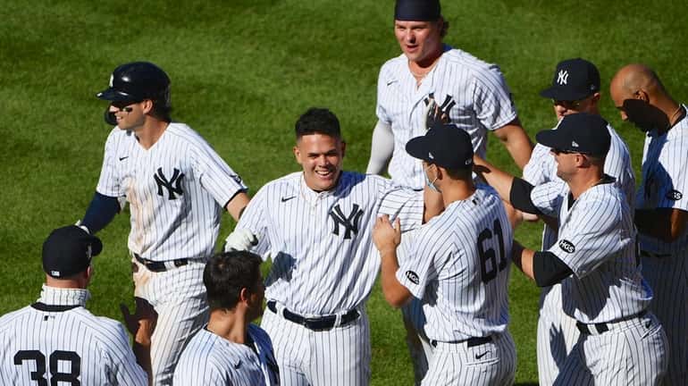 Yankees' Gio Urshela, center facing, is congratulated by teammates after...