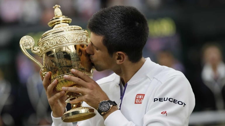 Novak Djokovic kisses the winner's trophy after beating Roger Federer...