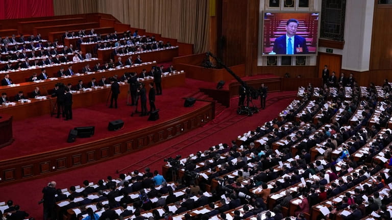A screen shows Chinese President Xi Jinping as delegates attend...