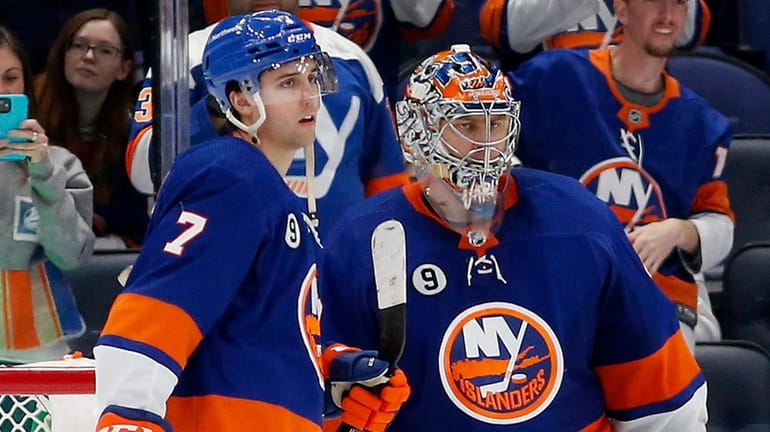 Semyon Varlamov and Grant Hutton of the Islanders celebrate after defeating the...