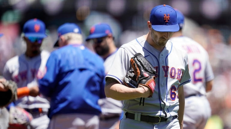 Mets pitcher Thomas Szapucki walks toward the dugout after being...