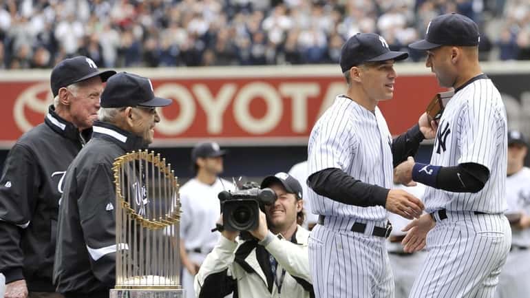 Yankees Whitey Ford and Yogi Berra watch Derek Jeter shake...