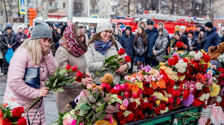 People lay flowers for the victims of a fire in...
