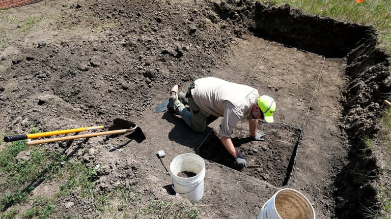Nebraska State Archeologist Dave Williams clears soil away soil as...