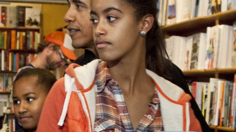 President Barack Obama shops with his daughters Malia, foreground, and...