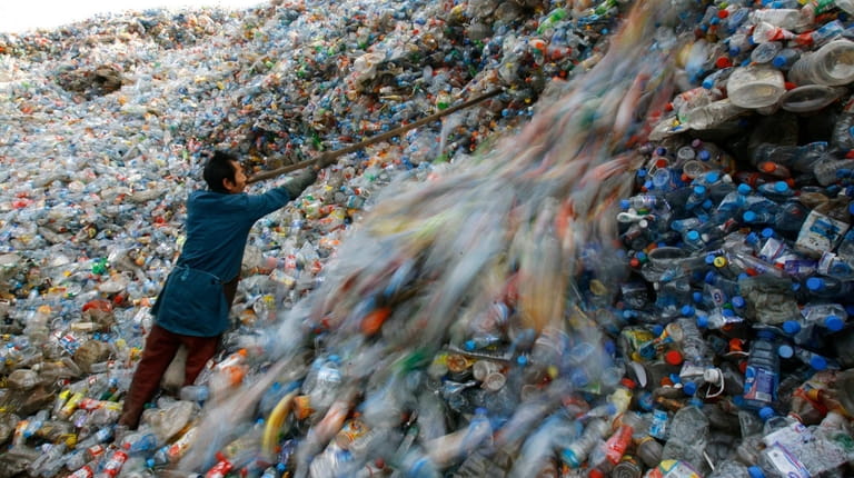 A worker sorts plastic bottles at a recycling center on...