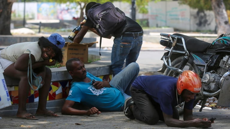 People take cover from gunfire during clashes between police and...