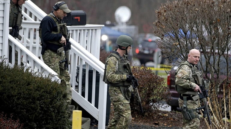 A police SWAT team walks out of the rectory of...