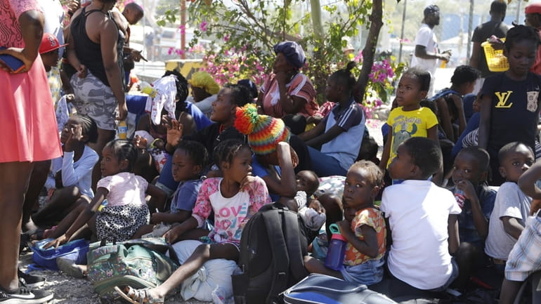 Children and their guardians gather outside a police station after...