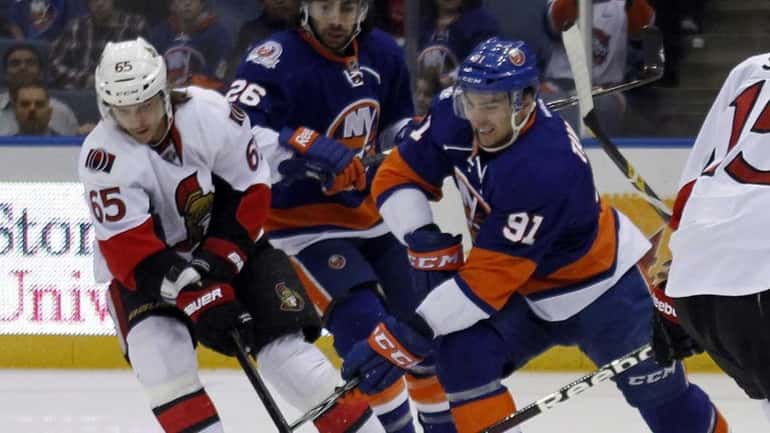 The Islanders' John Tavares battles for the loose puck against...