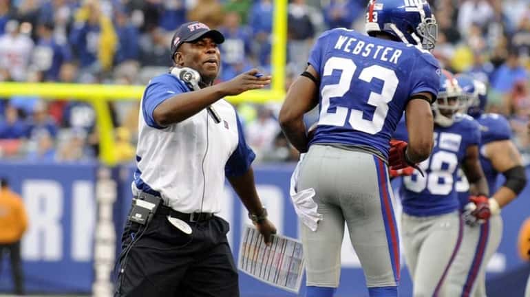 Defensive coordinator Perry Fewell greets Corey Webster on the sideline...