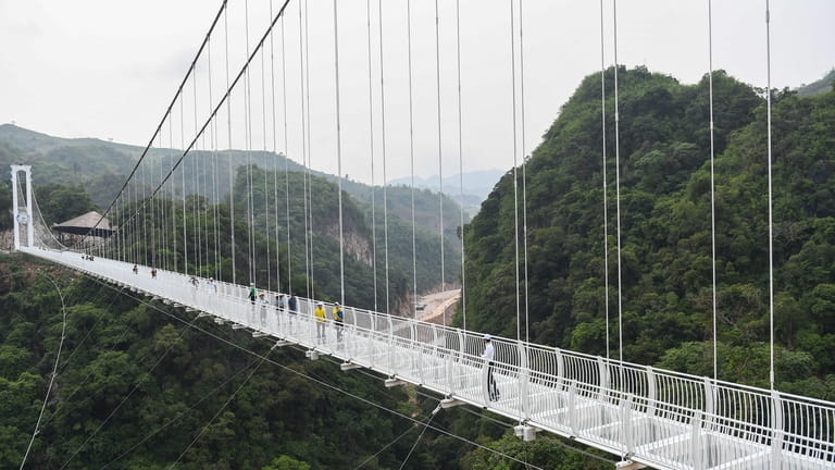 Visitors walk on the Bach Long glass bridge in Moc...