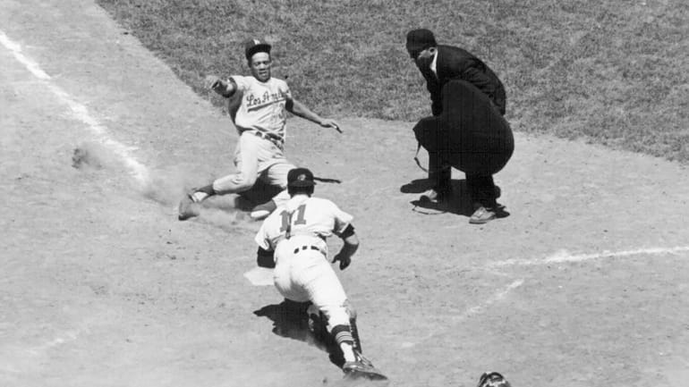 The Dodgers' Maury Wills slides safely home in the eighth inning of...