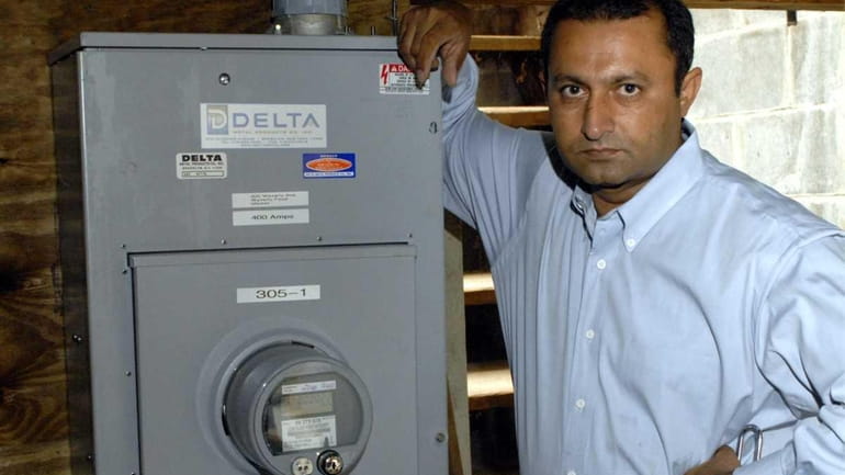 Ghulam Sarwar, seen next to the electric meter in his...