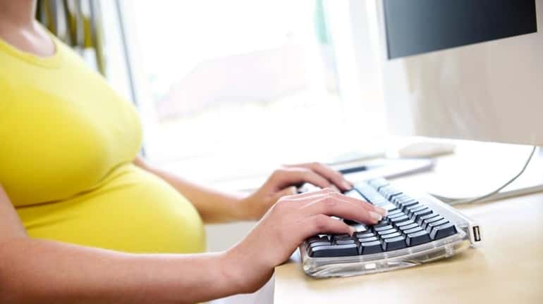 A pregnant woman at a computer.