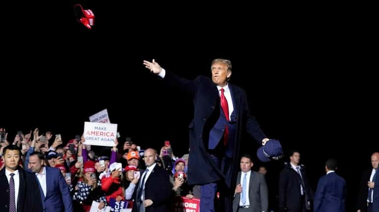 President Donald Trump tosses MAGA hats to supporters at a...