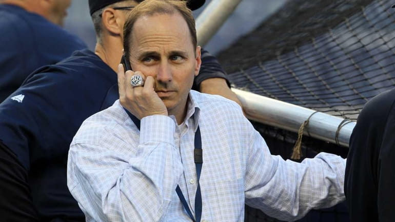 Yankees general manager Brian Cashman talks on the phone during...