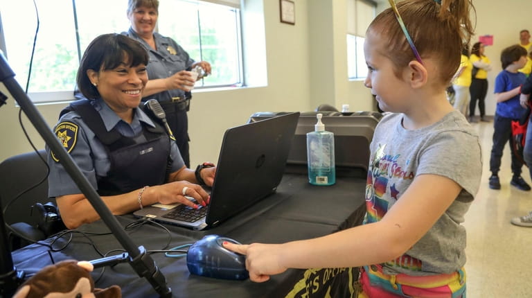 Lia Nicosia, 6, of Bayport has her fingerprints taken electronically for a...