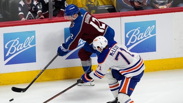 Colorado Avalanche right wing Brandon Duhaime, back, slips the puck...