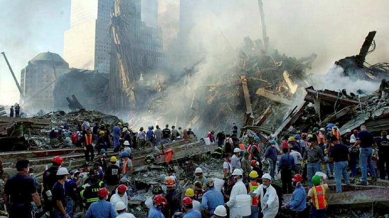 Rescue workers and volunteers remove debris at the World Trade...
