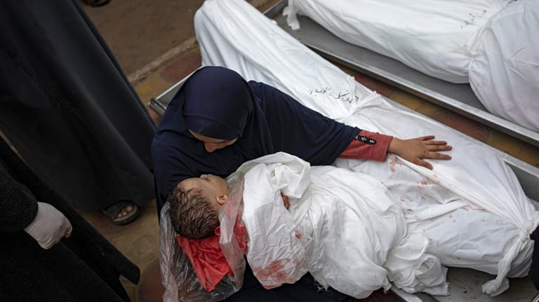 A woman mourns the bodies of her child and her...