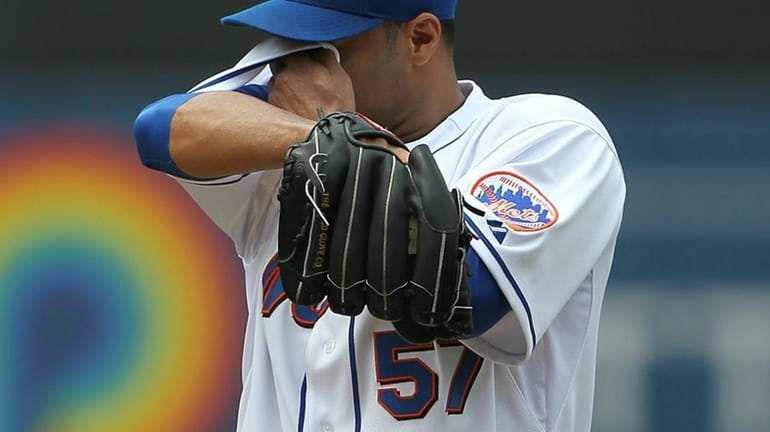 Johan Santana #57 of the New York Mets wipes sweat...