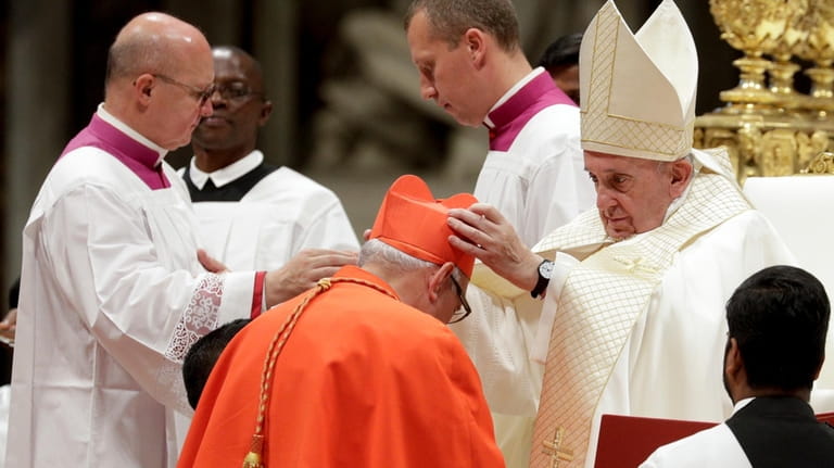 Cardinal Alvaro Ramazzini receives the red three-cornered biretta hat from...