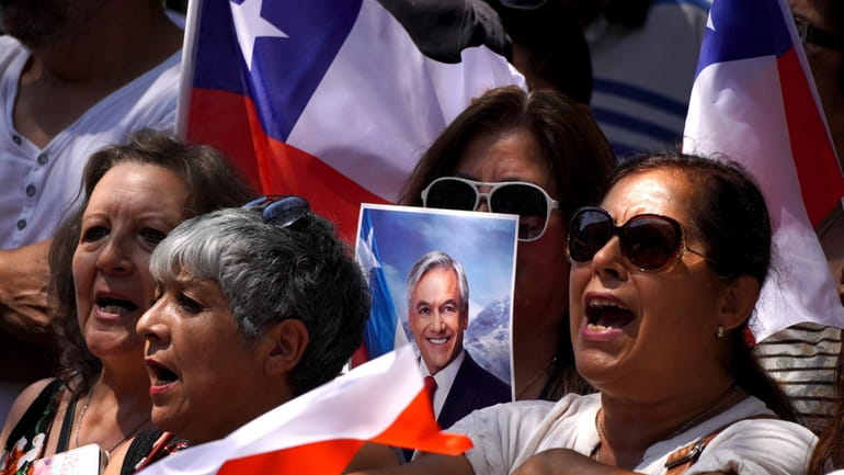 People sing Chile's national anthem outside Congress as they wait...