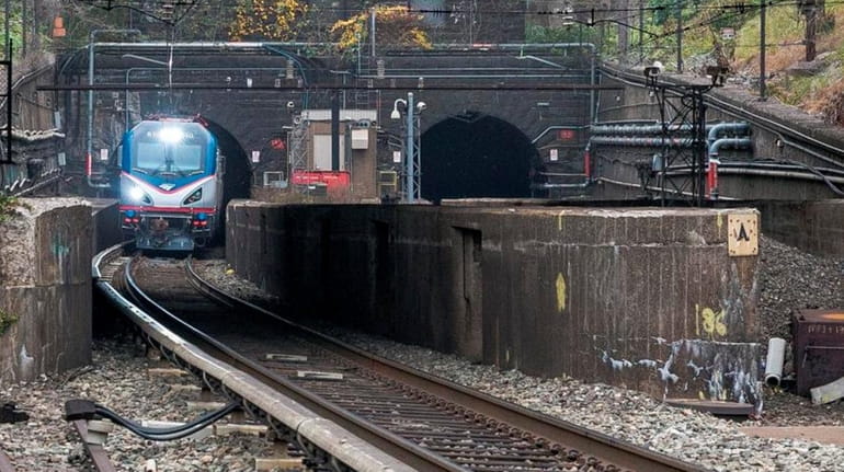 An Amtrak locomotive emerges from the North River Tunnel in...