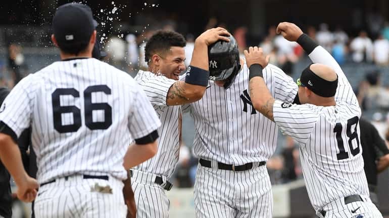Yankees designated hitter Aaron Judge is congratulated by teammates after...