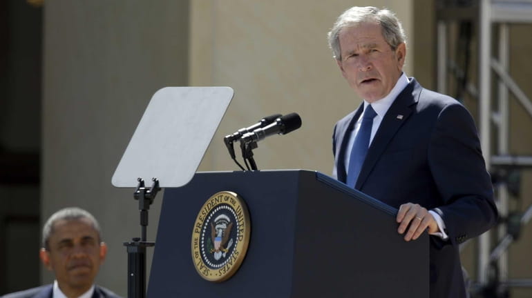 President Barack Obama listens as former President George W. Bush...