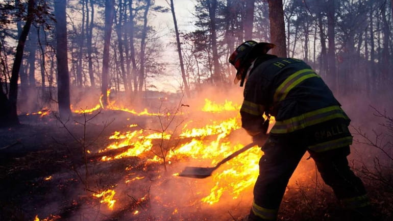 A firefighter battles a blaze in Manorville off Wading River...
