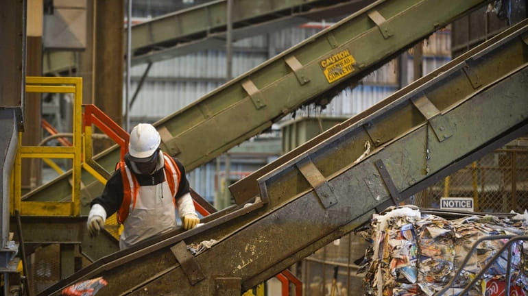 Employees sort recyclables on machines at Brookhaven Town's waste management...