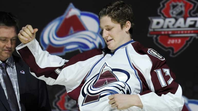 Nathan MacKinnon, a center, pulls on a Colorado Avalanche sweater...
