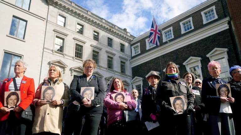 Colleagues of police constable Yvonne Fletcher hold photos of her...