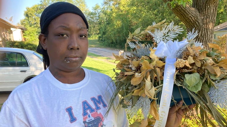 Ericka Lotts holds a bouquet from the funeral of her...