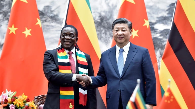 Zimbabwean President Emmerson Mnangagwa, left, shakes hands with Chinese President...