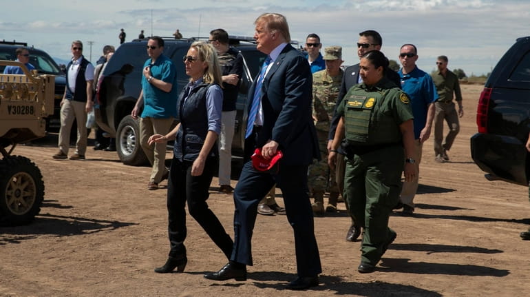 Homeland Security Secretary Kirstjen Nielsen walks with President Donald Trump...