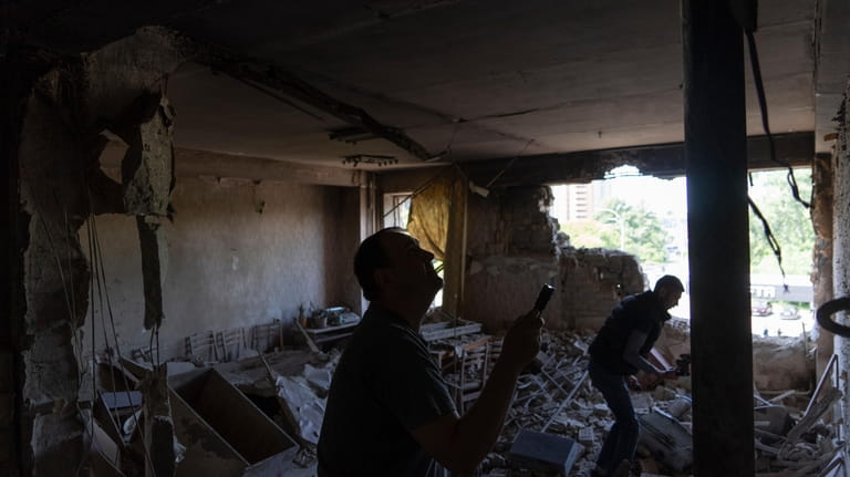 Men inspect their office damaged by a drone during a...