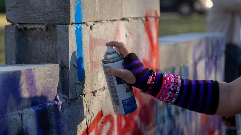 Teens spray paint a cinder block wall during the LGBT...
